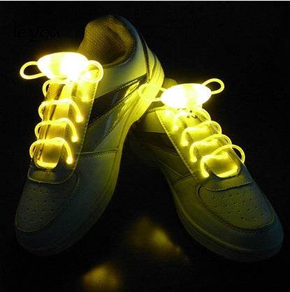 LED sport shoe laces glowing brightly on sneakers in the dark.
