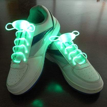 Led sport shoe laces glowing in green on white sneakers.