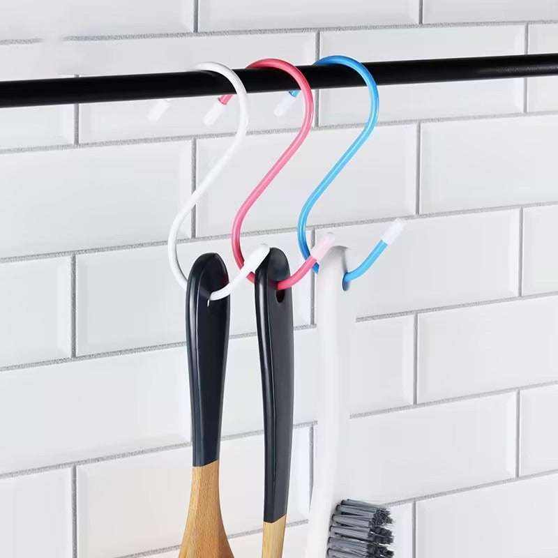 Four multicolored rubber S-hooks hanging on a kitchen rod.