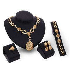 Four-piece jewelry set with necklace, earrings, bracelet, and ring in gold alloy, featuring bamboo link chain and love/water drop/bell patterns.
